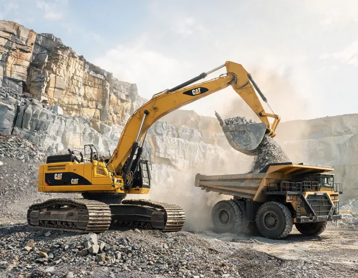 Caterpillar crawler excavator loading aggregate at quarry face